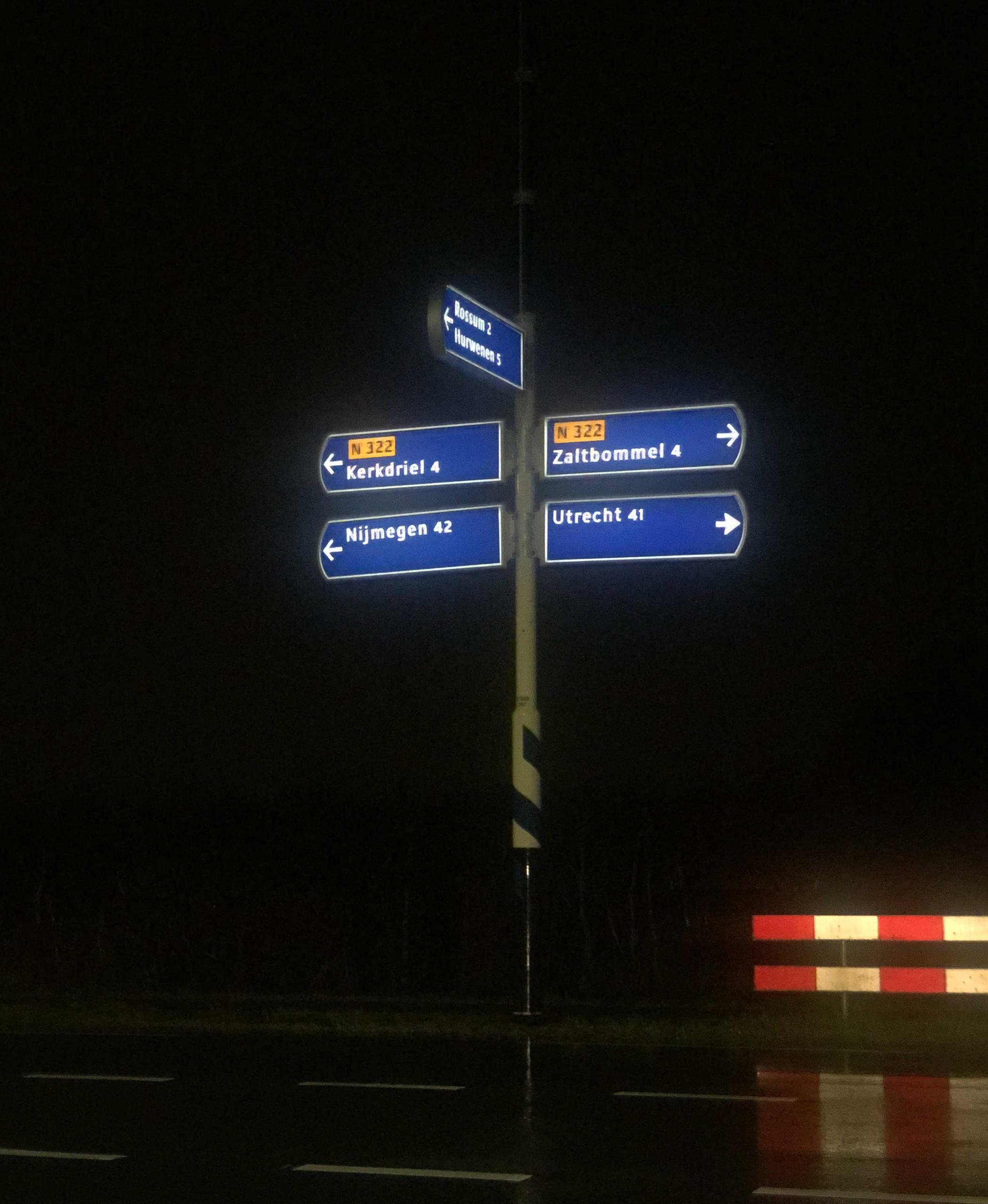 The Soluxio solar-powered sign post at night, with internally illuminated directional signs