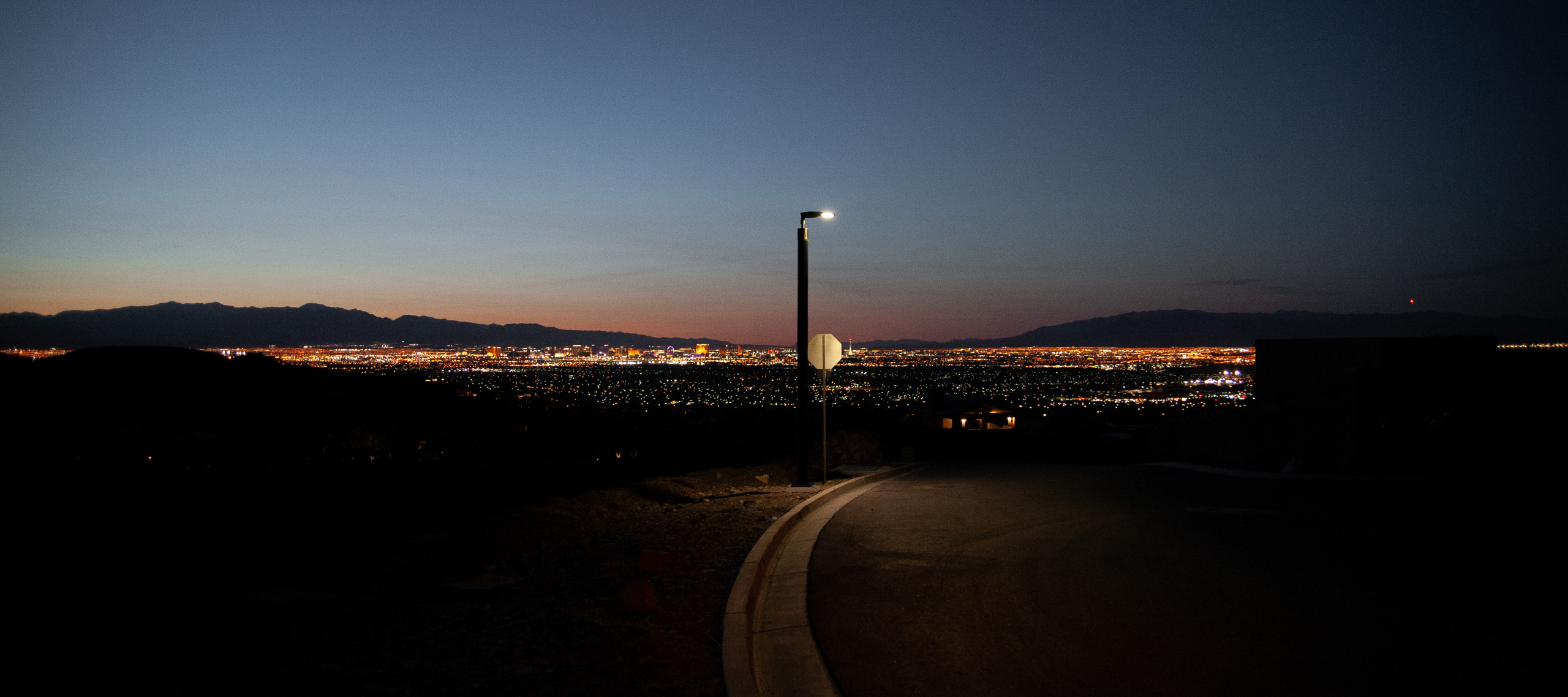 Soluxio solar street light illuminating a hillside road at dusk with the Las Vegas skyline in the background.