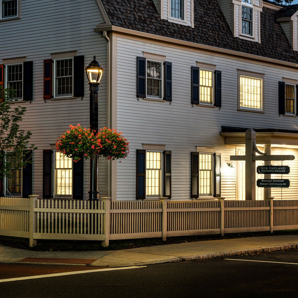 Soluxio solar street lights with classic city fixtures and flower plant hangers illuminating a street in Topsfield at night